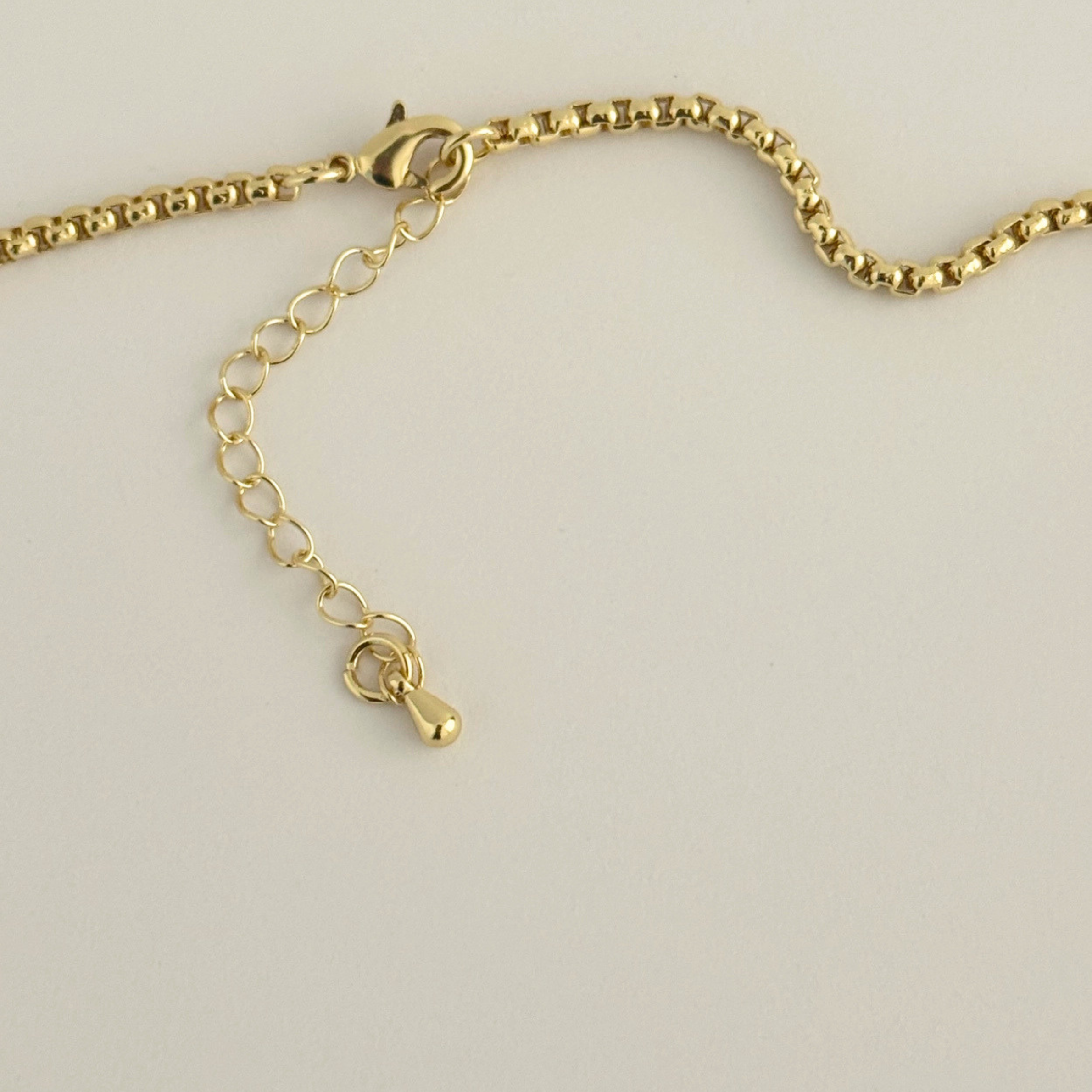 a gold necklace with a clear quartz stone in the center as a pendant. 