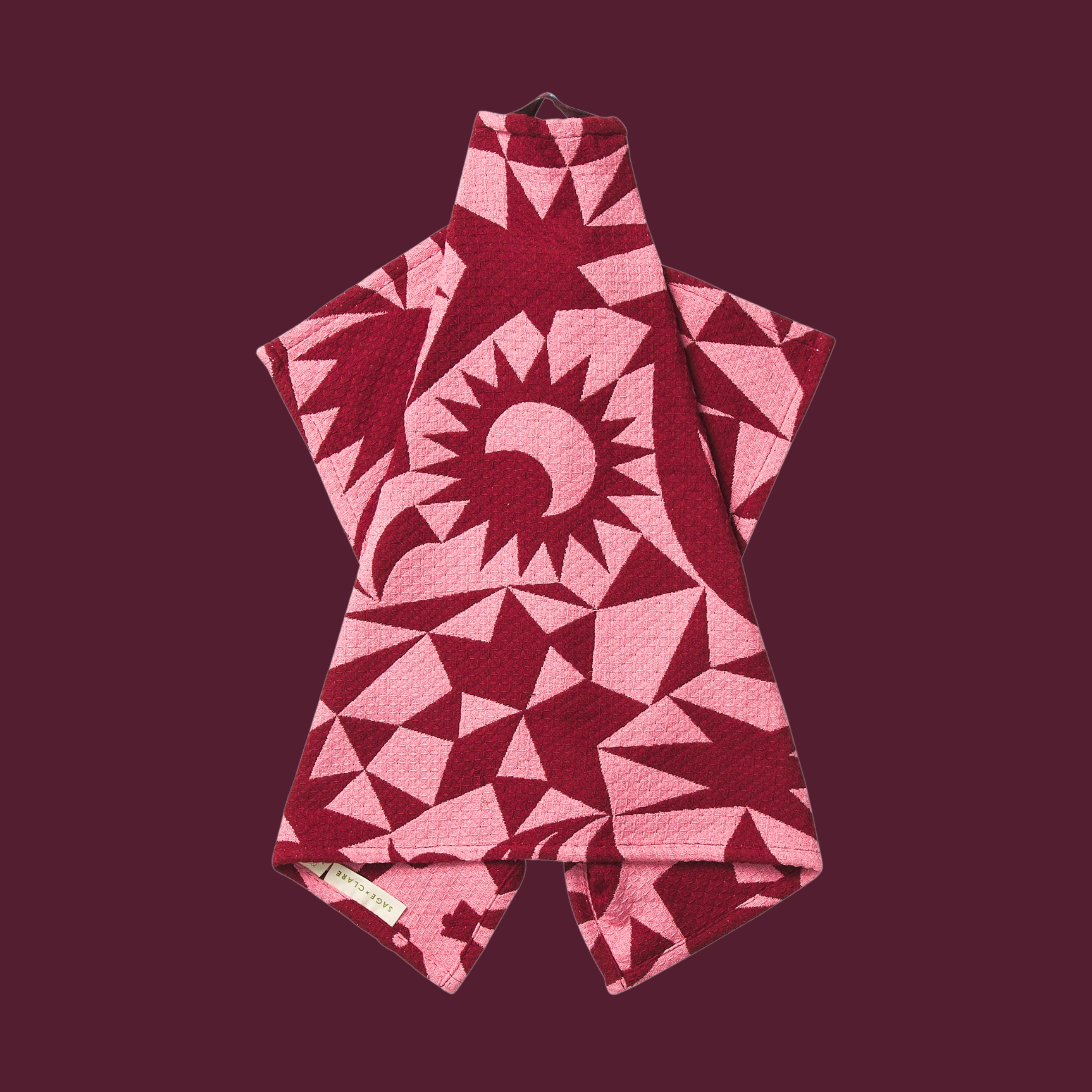 a pink and burgundy geometric patterned waffle knit tea towel.