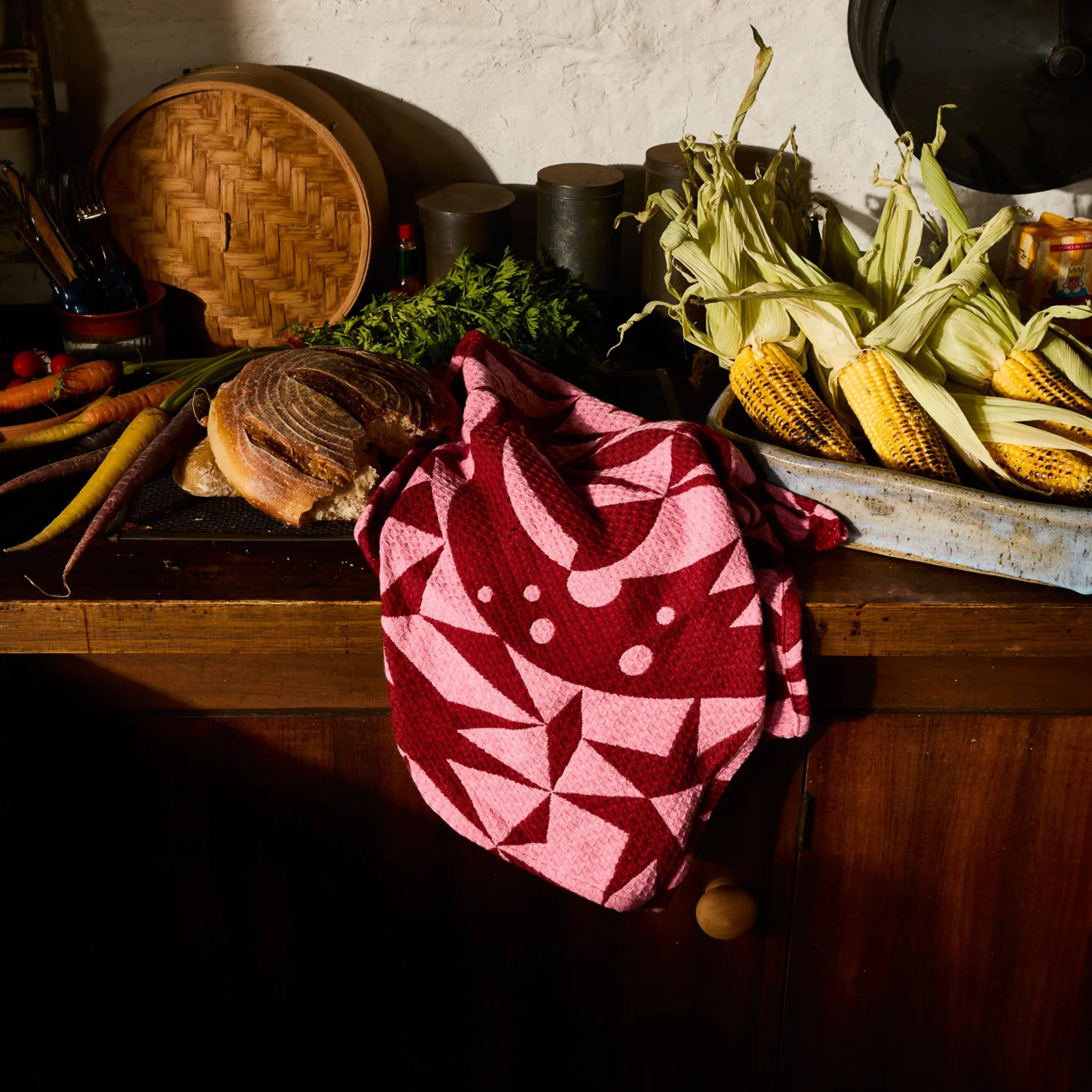 a pink and burgundy geometric patterned waffle knit tea towel.