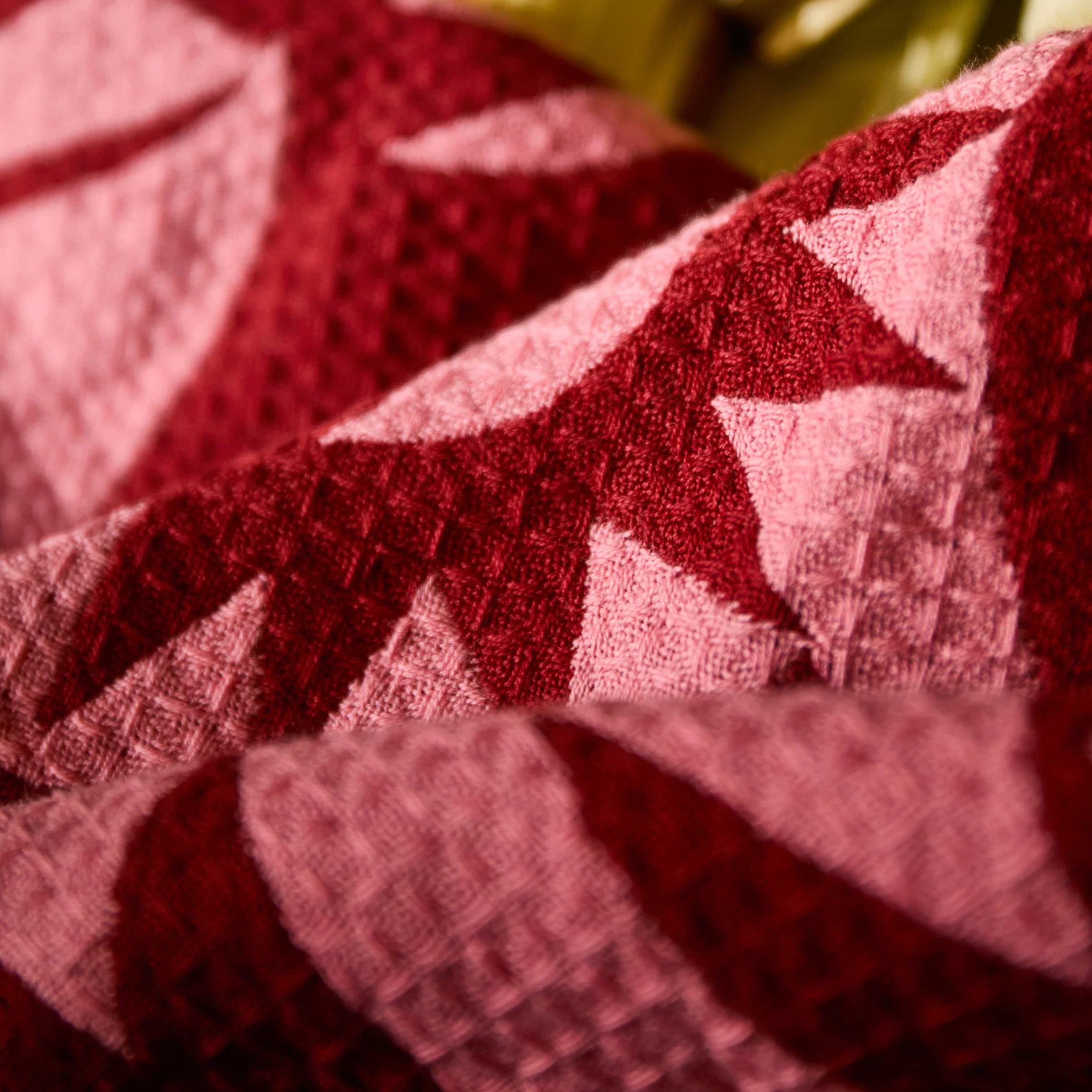 a pink and burgundy geometric patterned waffle knit tea towel.