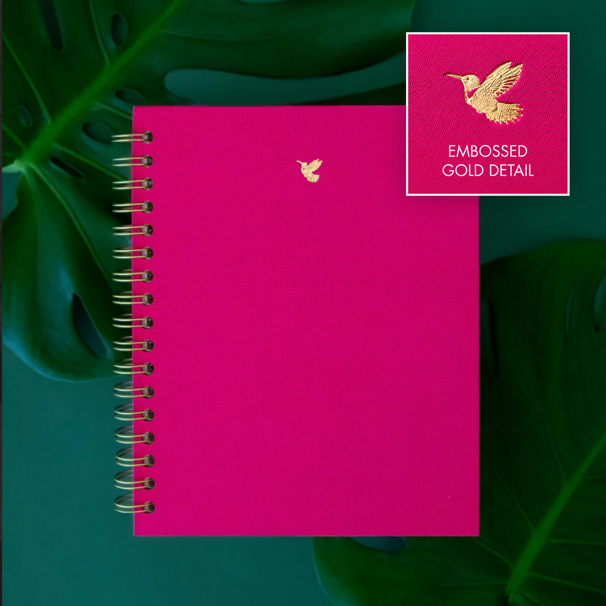 Close up detail of a gold hummingbird emobssed on a pink notebook.
