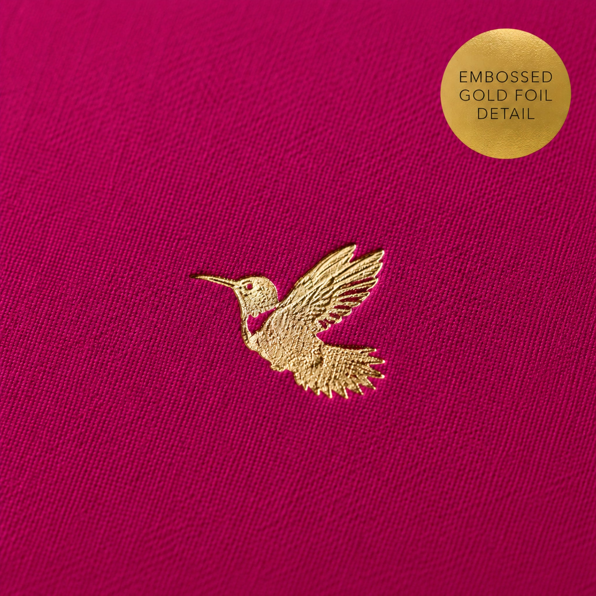 Close up detail of a gold hummingbird emobssed on a pink notebook.