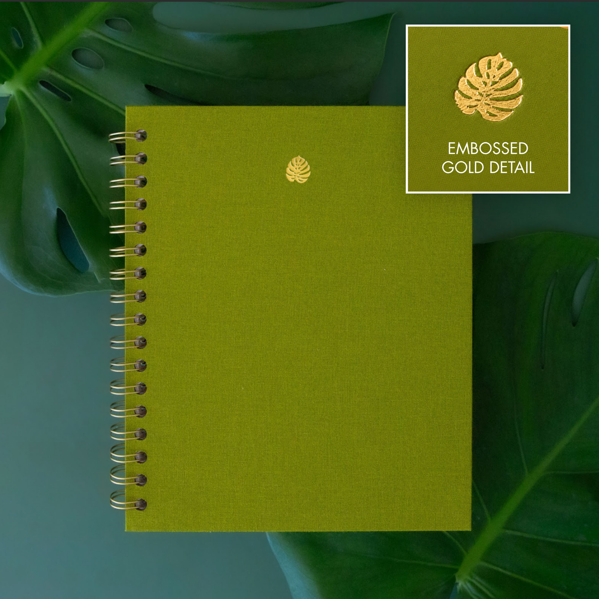 Detail photo of a gold embossed monstera leaf on a green notebook.