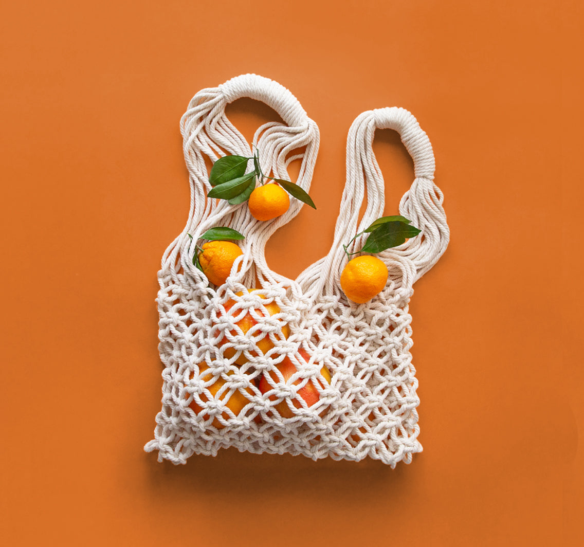 White macrame bag with oranges on an orange background