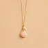 a gold necklace with a pearl and shell shaped pendant. 