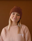 A brown knit beanie. 