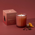 a reddish colored boxed candle with a ribbed texture and a single wick. 