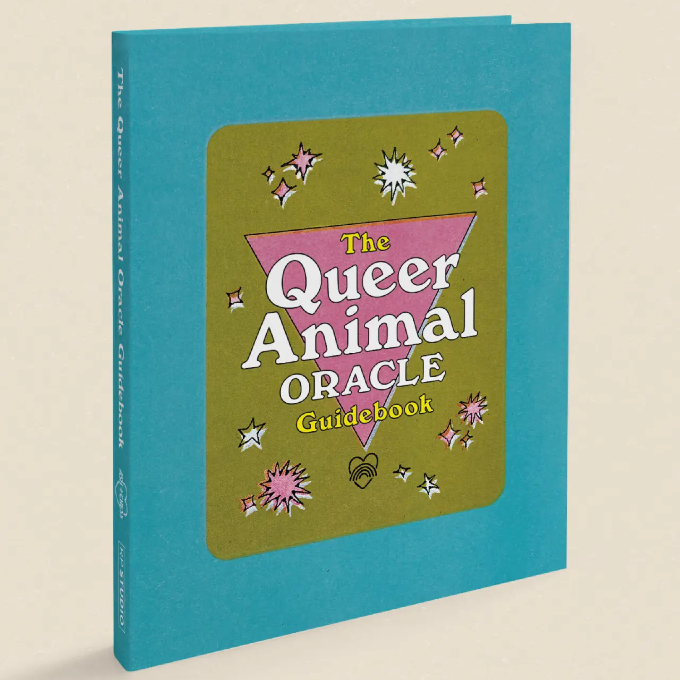 The Queer Animal Oracle Guidebook, featuring a turquoise blue hardcover with a central olive green cover insert. The insert displays a pink inverted triangle and white text reading 'The Queer Animal Oracle Guidebook' with small pink and white star illustrations.
