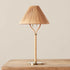 A neutral rattan table lamp with a brass base, bamboo wrapped post and a woven lampshade. 