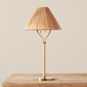 A neutral rattan table lamp with a brass base, bamboo wrapped post and a woven lampshade. 