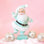 On a pink background is a Santa figurine wearing a mint colored suit with the fluffy details. 