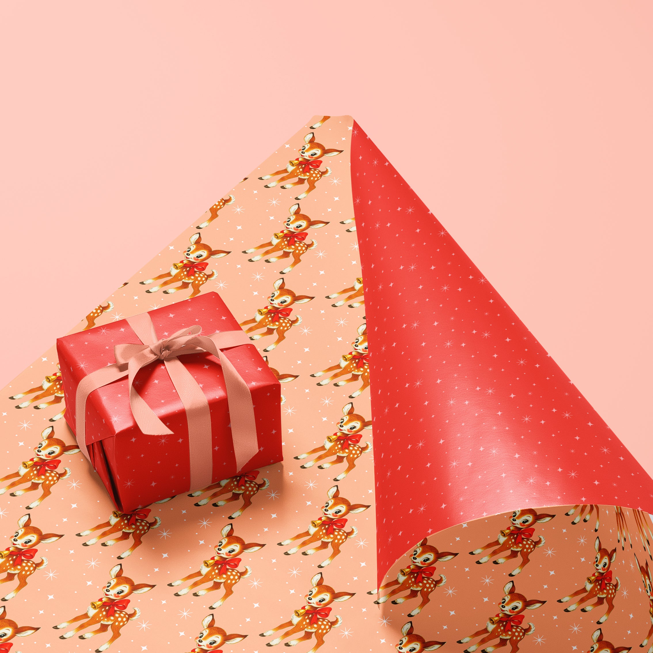 Holiday wrapping paper. One side is light orange with retro inspired deers and the other side is bright red with white stars. 