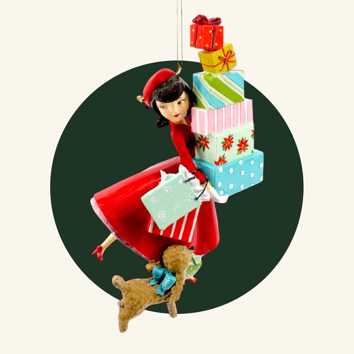 A resin ornament of a lady in a red dress with black hair holding lots of Christmas packages and a brown dog at her side.