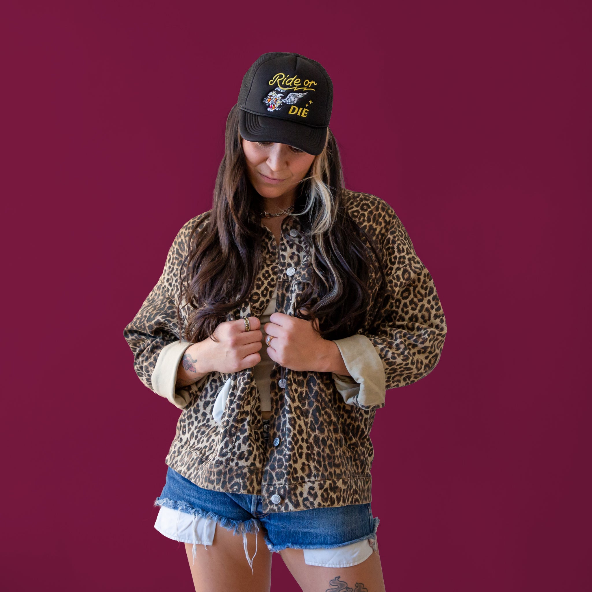 Model wearing a black trucker hat that reads " Ride or Die".