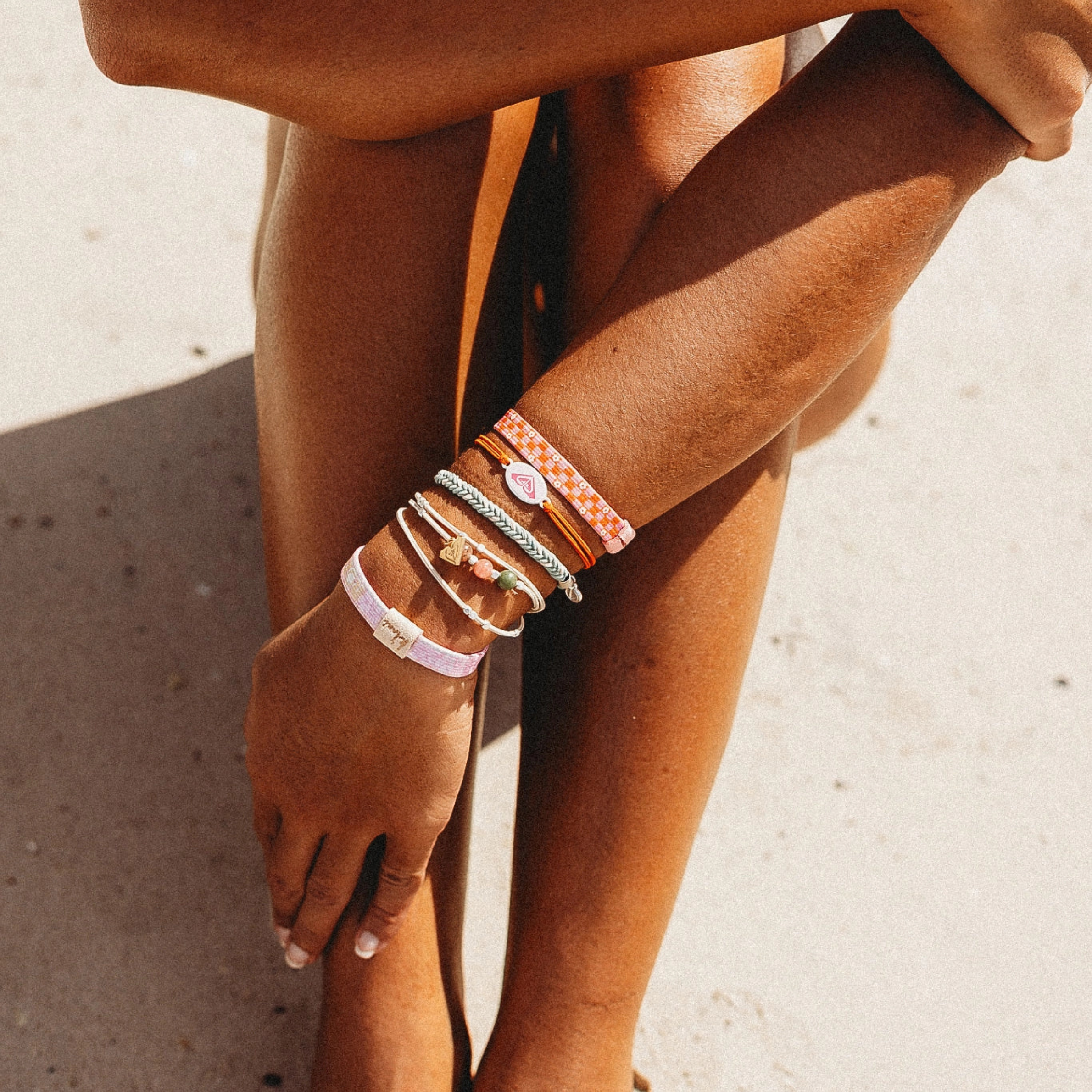 Close-up of a person's arm with multiple bracelet hair ties on a neutral background