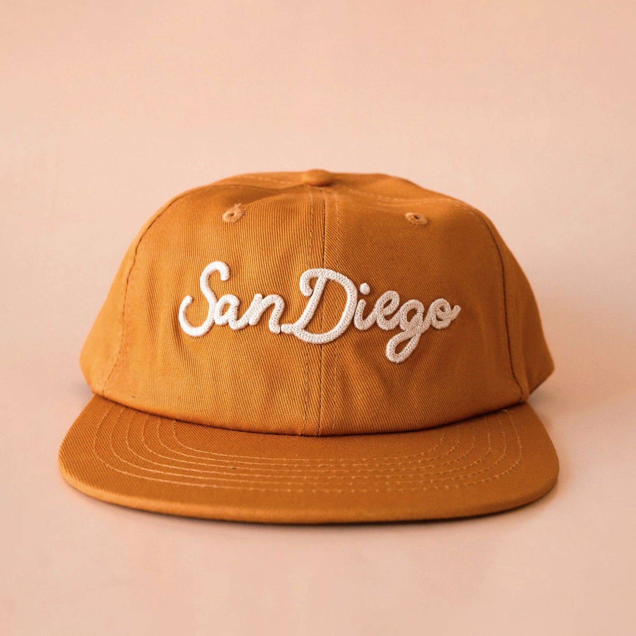 A tan colored hat with white embroidery that reads "San Diego"