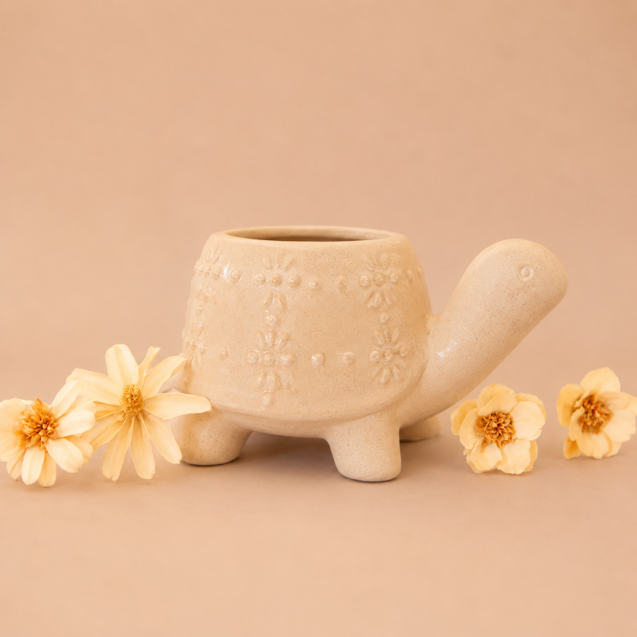 a ceramic planter in the shape of a turtle with a light tan "shell" with a subtle speckle detail.