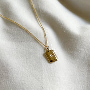 A gold rectangle pendant necklace with a cz stone in the center. 