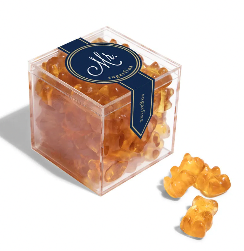 On a white background is a clear acrylic box with orange/brown gummy bears. 