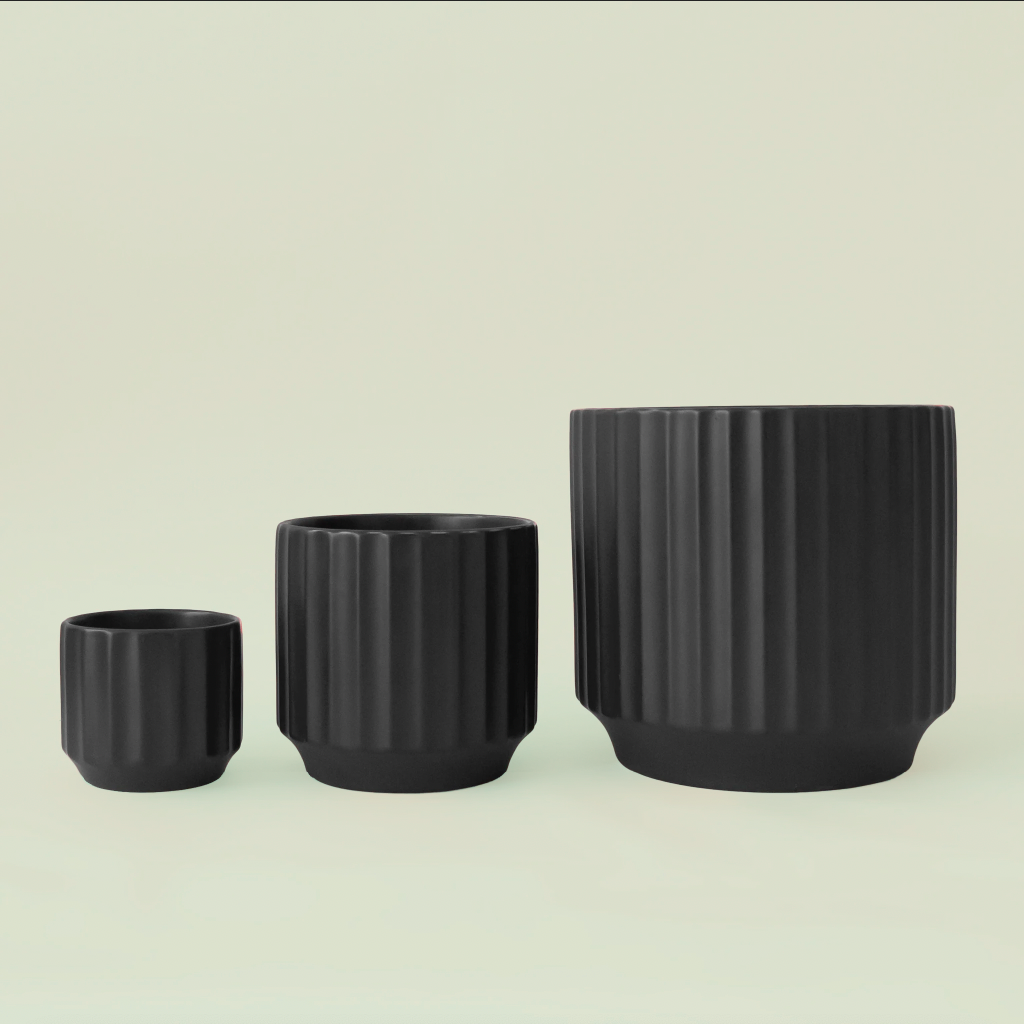 A black fluted ceramic planter with a plant inside sold separately. 