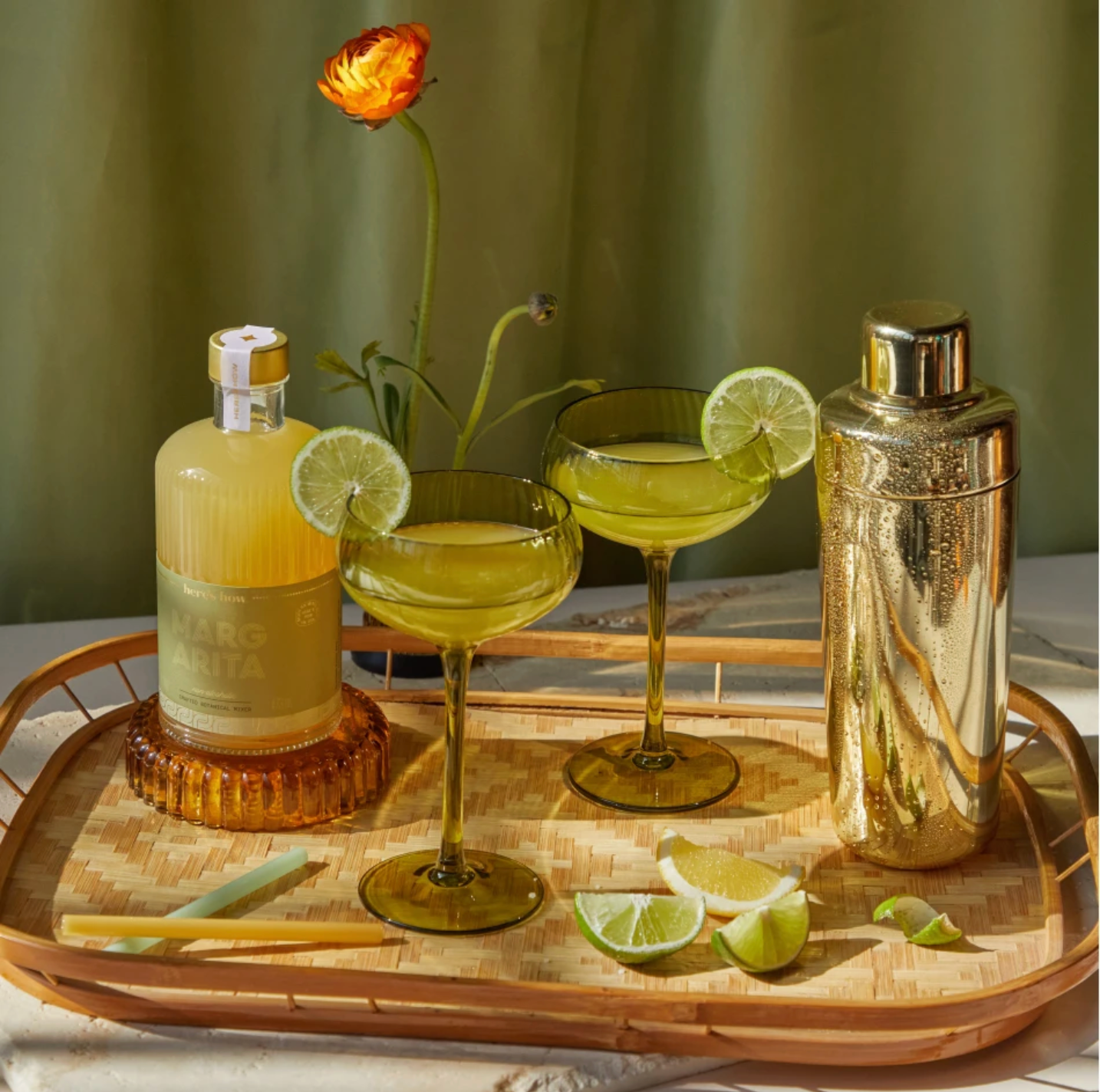 Olive green coupe glasses on a rattan tray.