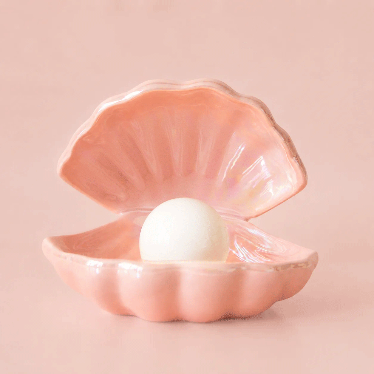 Gif of a pink ceramic seashell night light turning on and off.