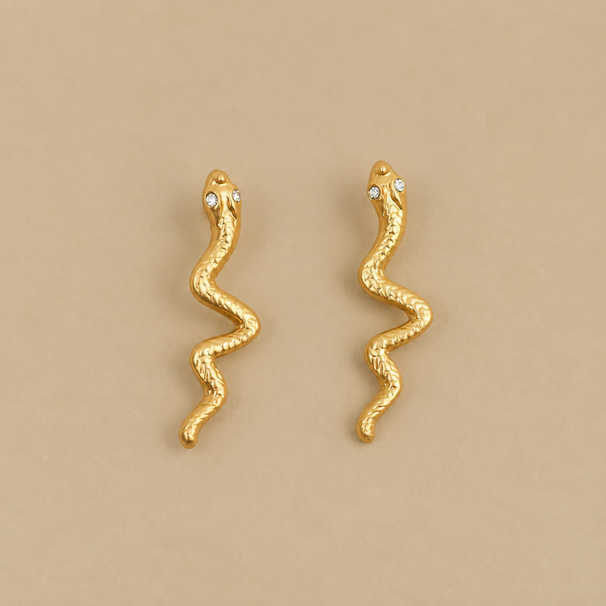 a pair of gold snake shaped earrings. 