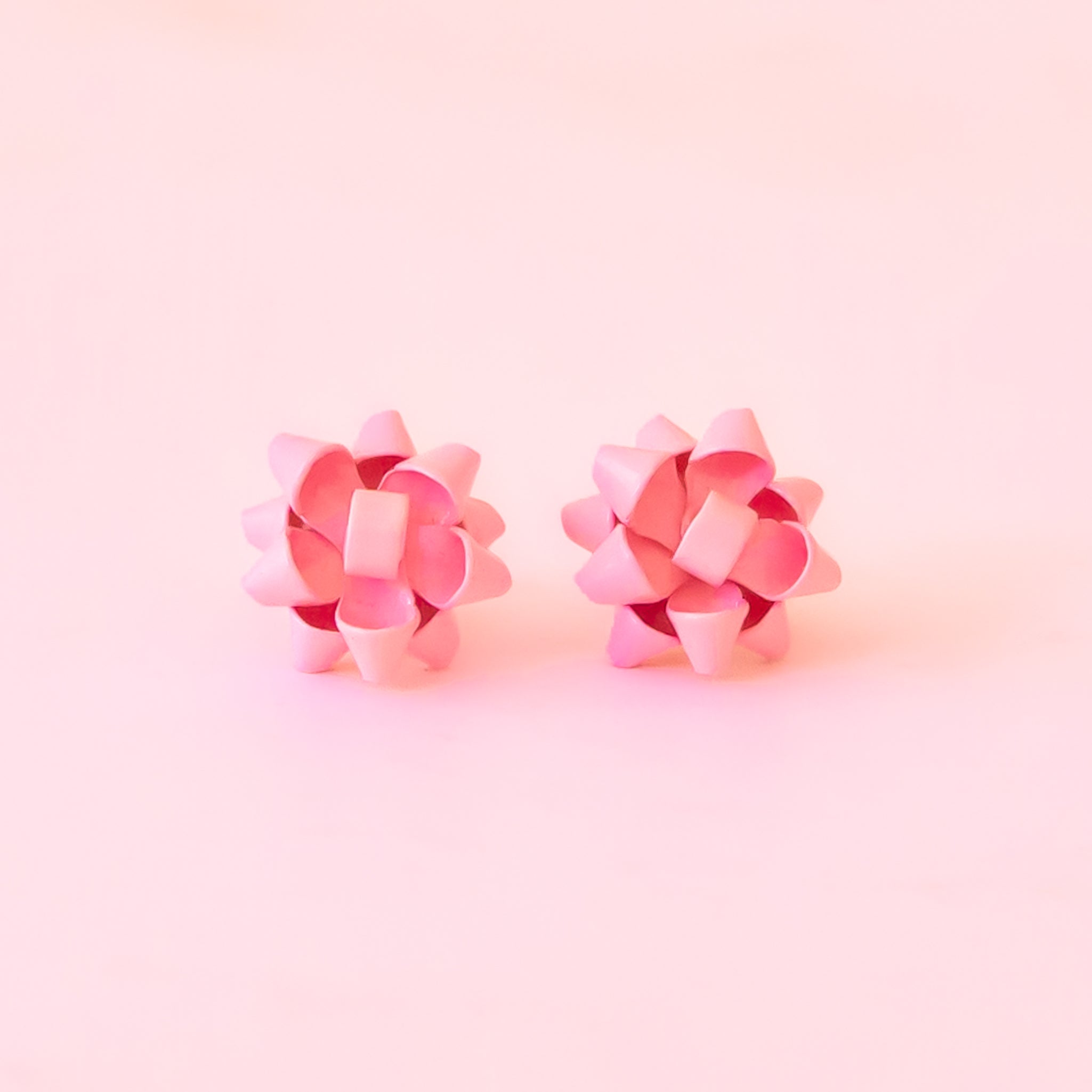 A pink pair of bow shaped earrings