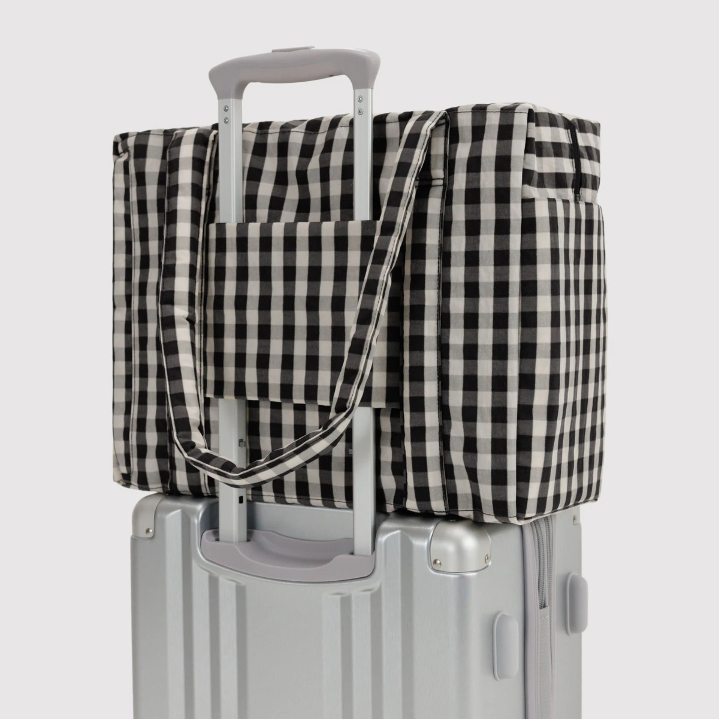 A black and cream gingham print nylon carry on bag.