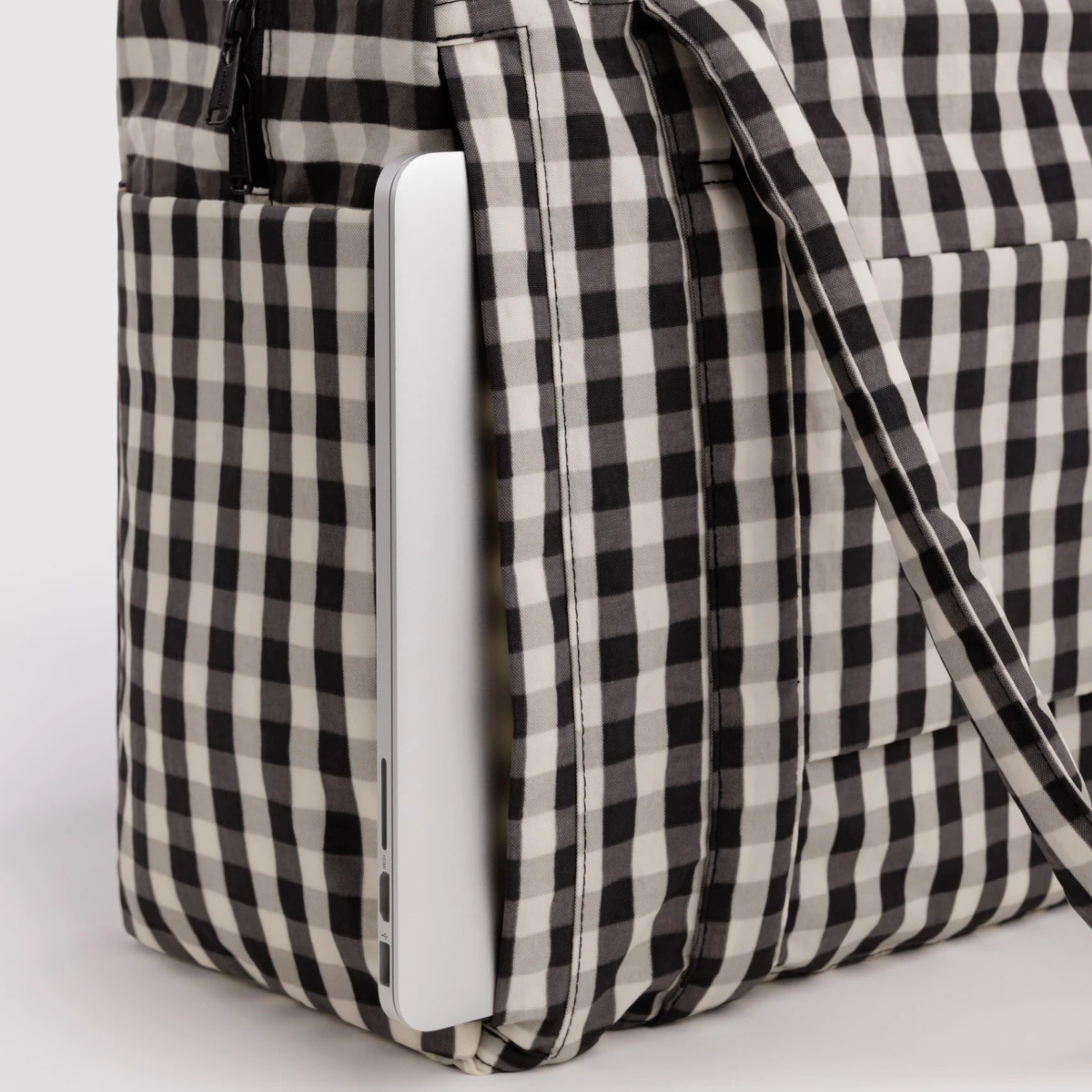 A black and cream gingham print nylon carry on bag.