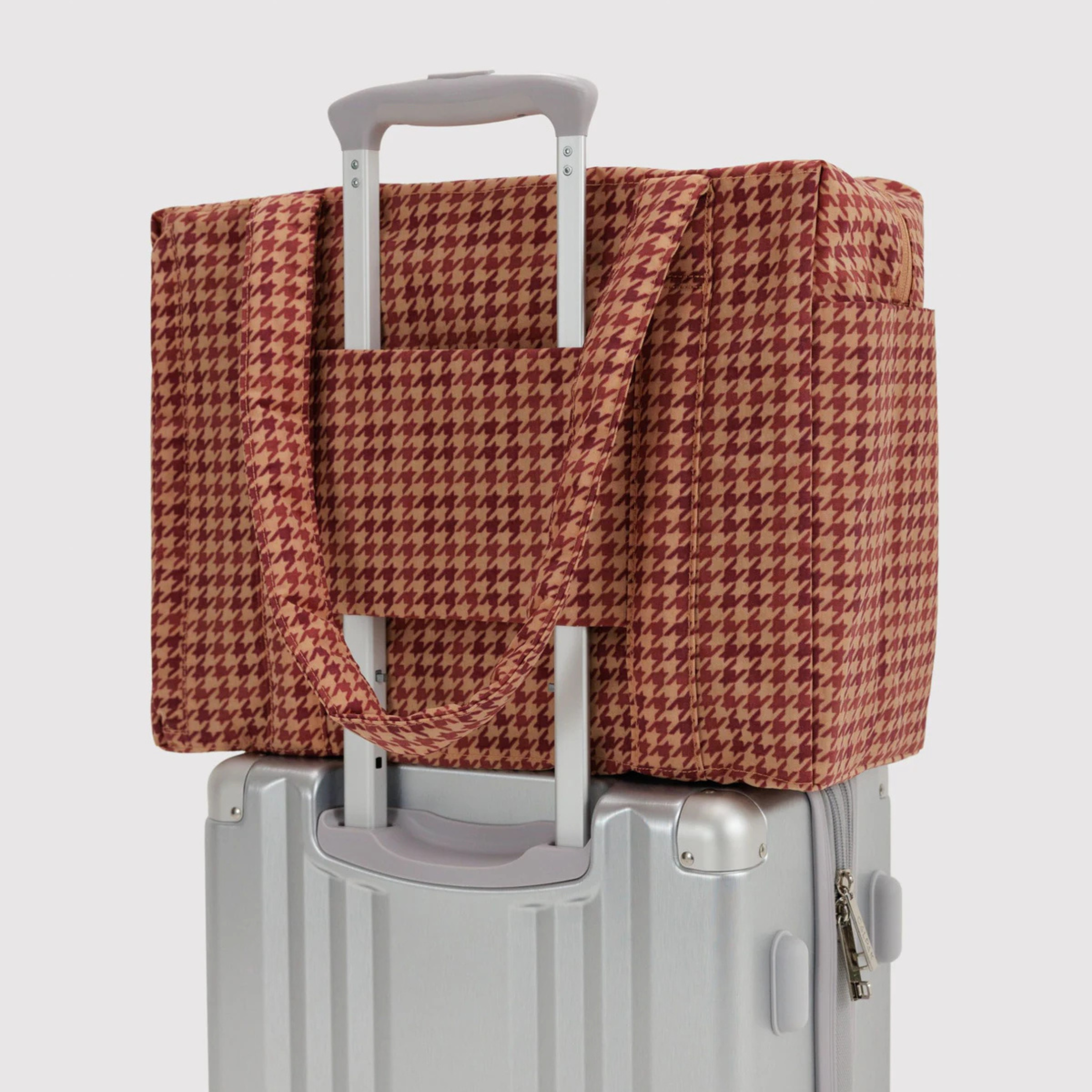 A tan and rust colored printed nylon carry on bag.