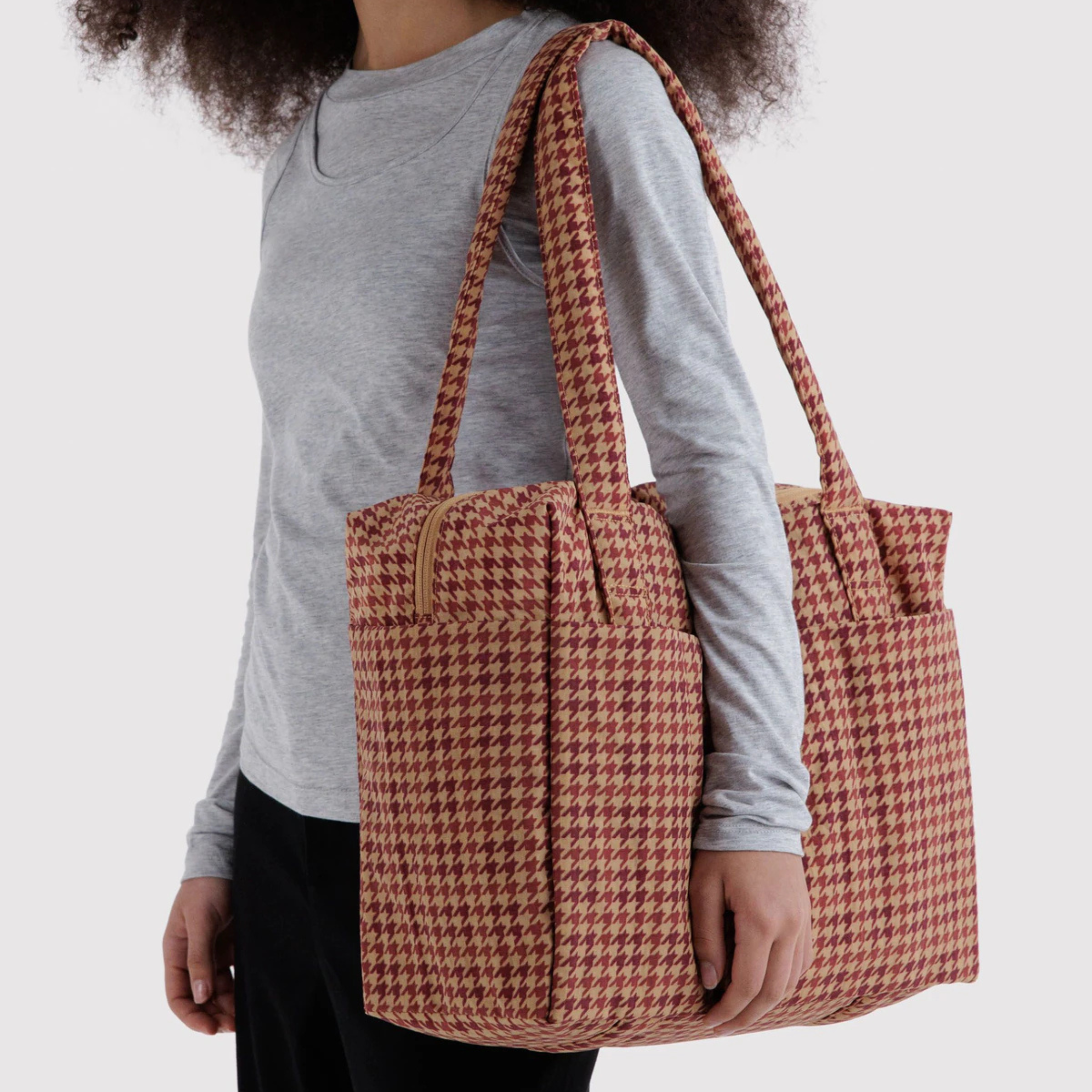 A tan and rust colored printed nylon carry on bag.