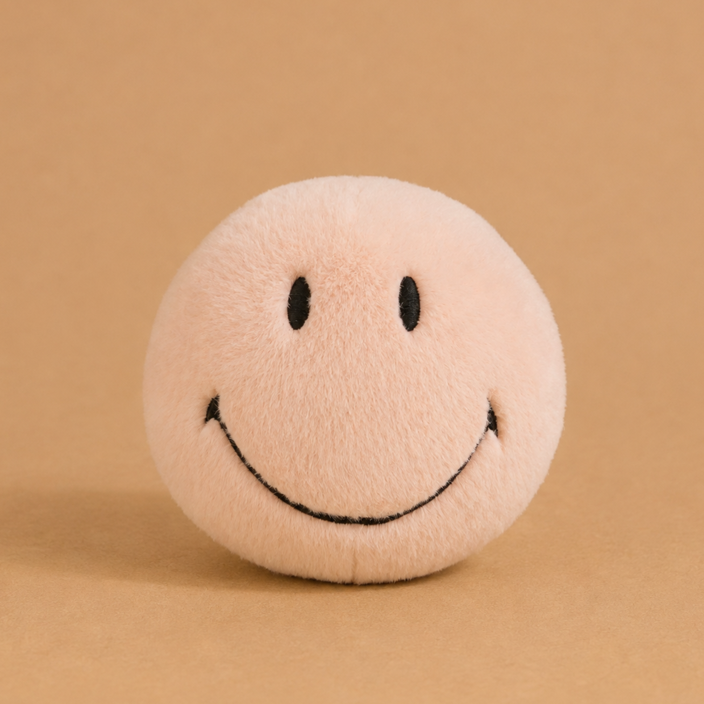 a pink round smiley face plush toy. 
