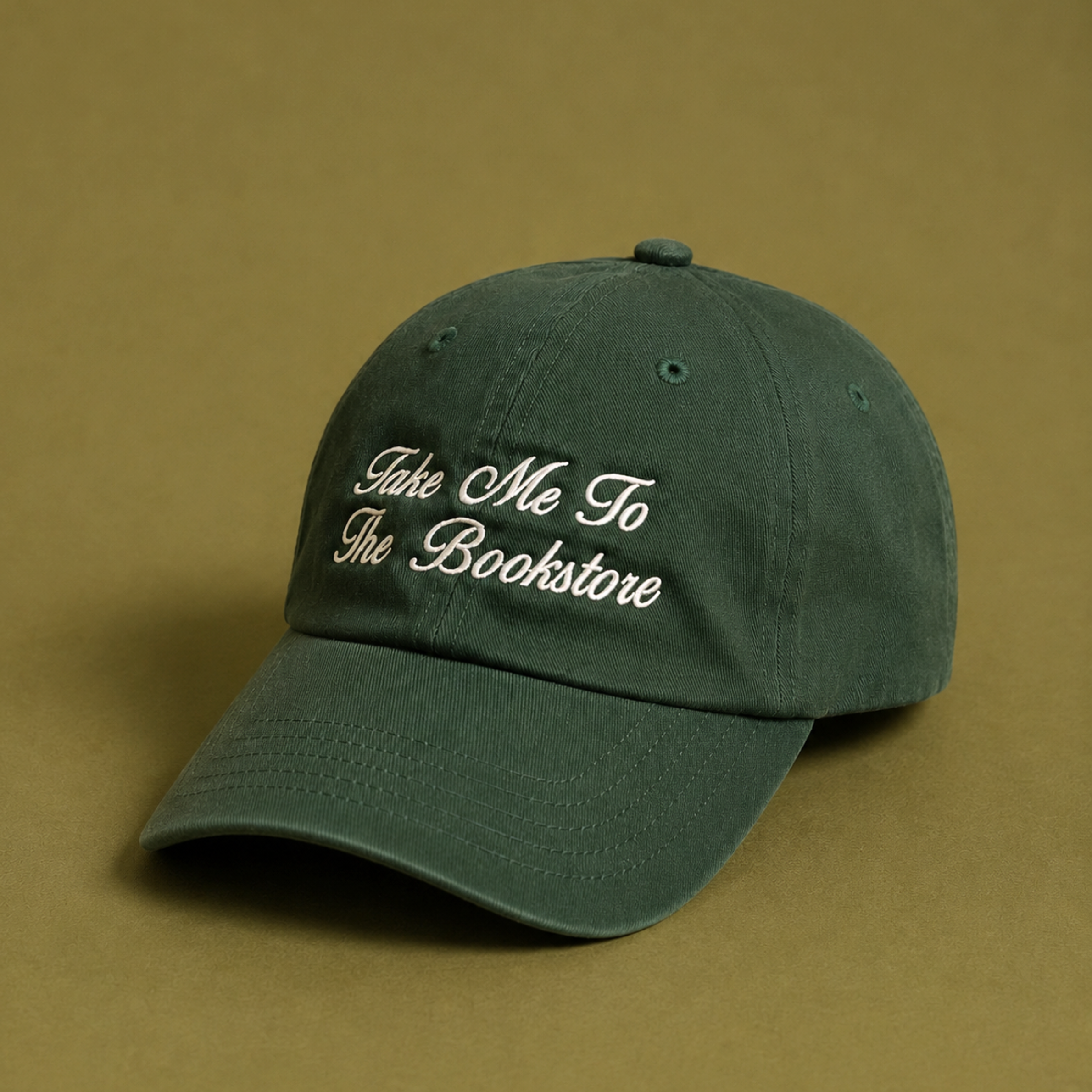 a green baseball cap with white embroidery that reads, "take me to the bookstore"
