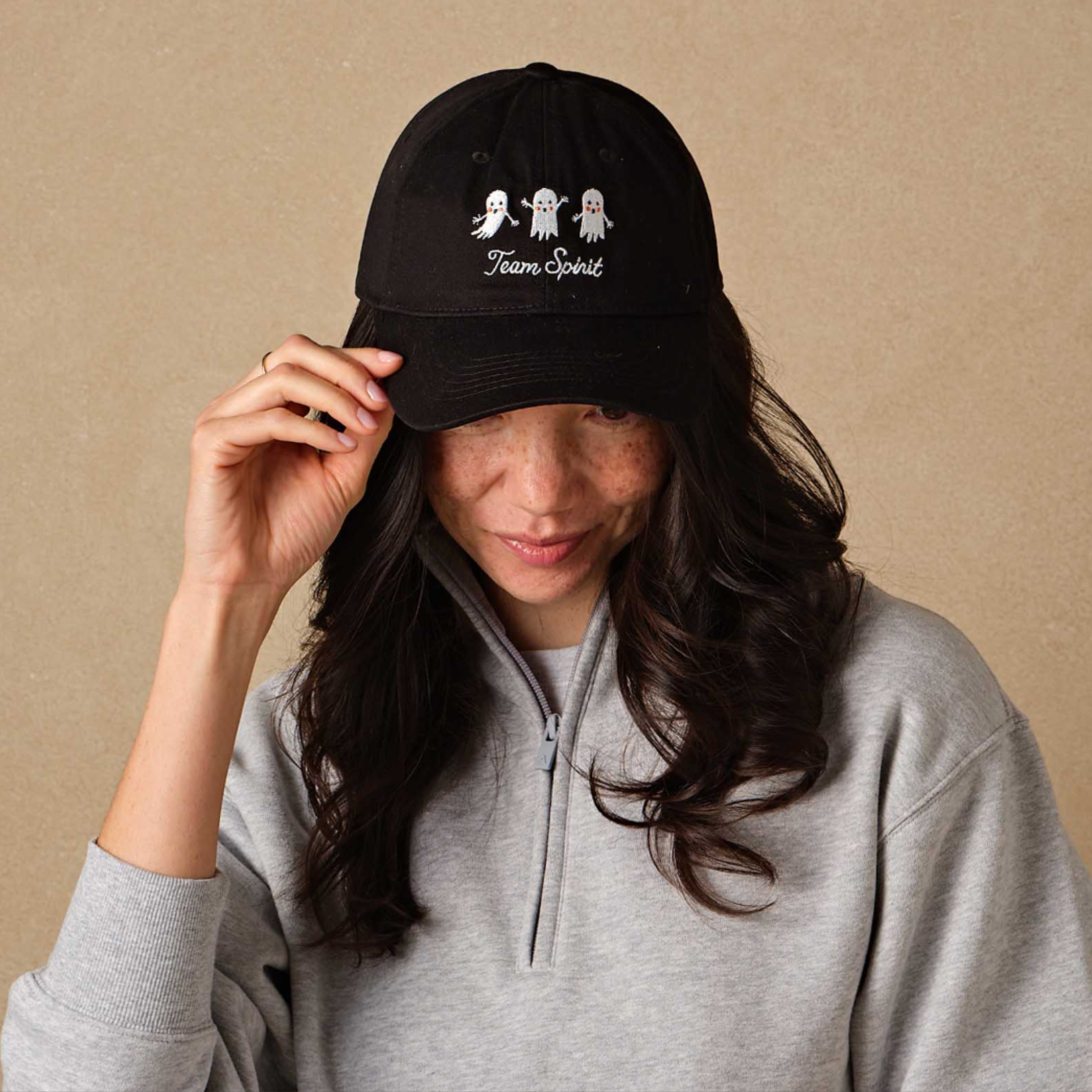 a black baseball hat with white embroidered text that reads, "Team Spirit" with three embroidered ghosts. 