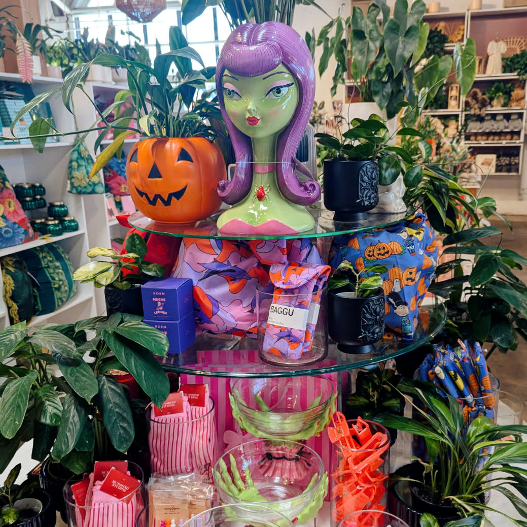 A stylized bust sculpture of a female character with long purple hair, green skin, and a pink collar featuring a red jewel, set against a solid dark gray background.