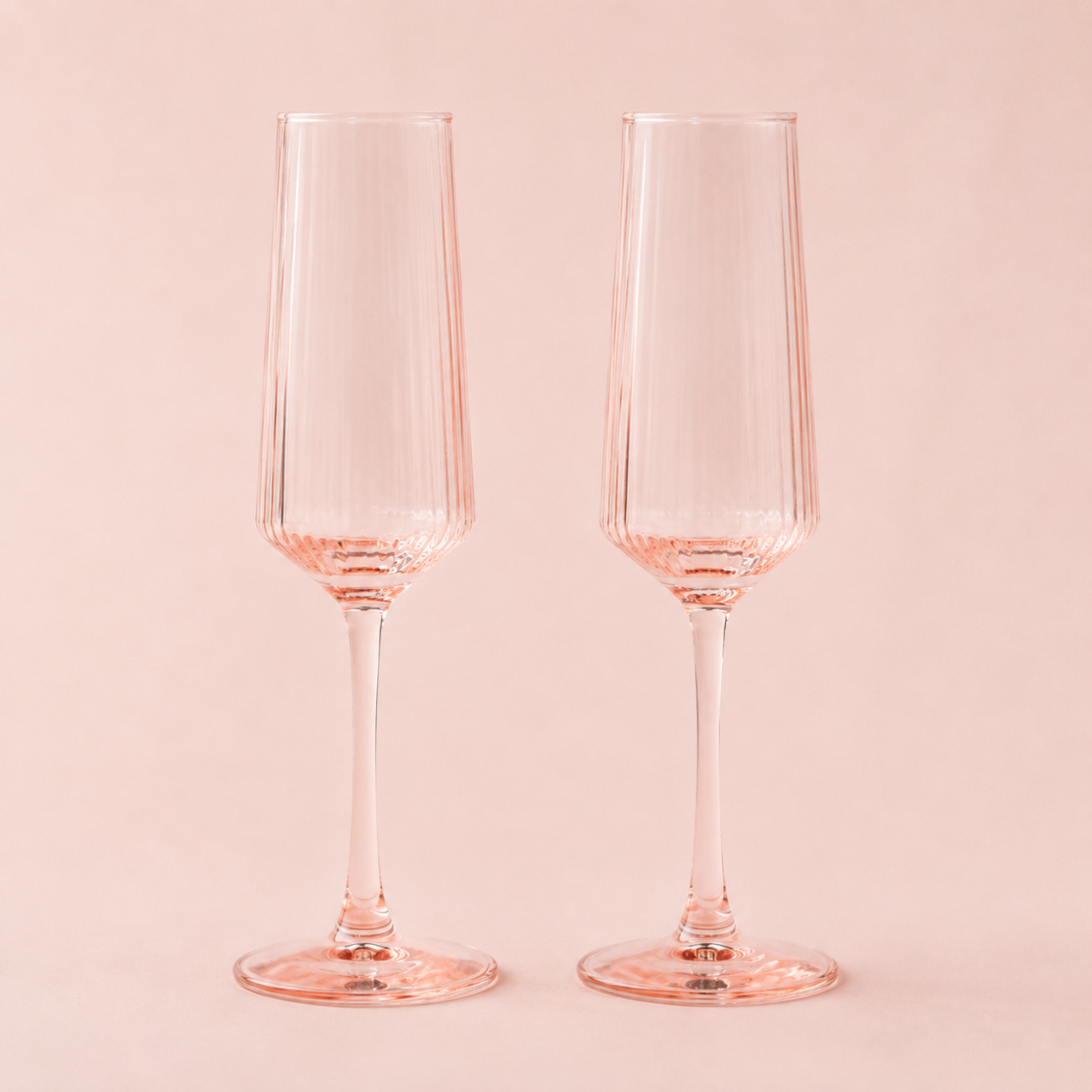 A set of blush pink champagne flute glasses.