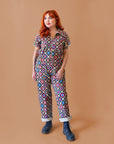 A multi-colored short sleeve jumpsuit with a zipper up the front and a floral pattern. 