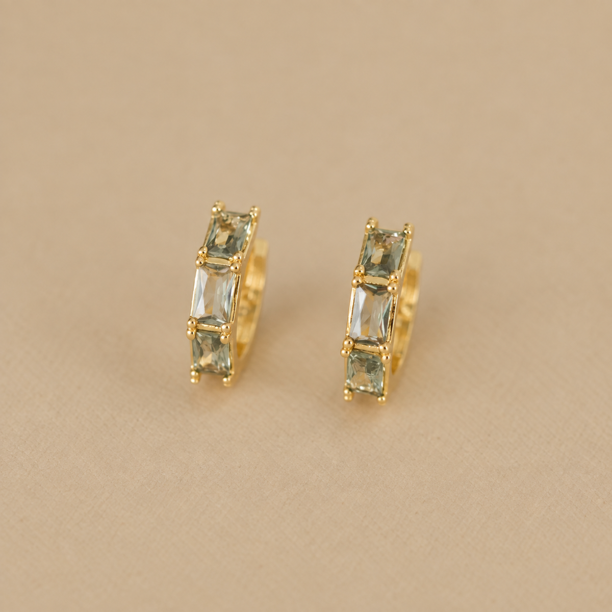 a pair of gold hoop earrings with stones inside. 