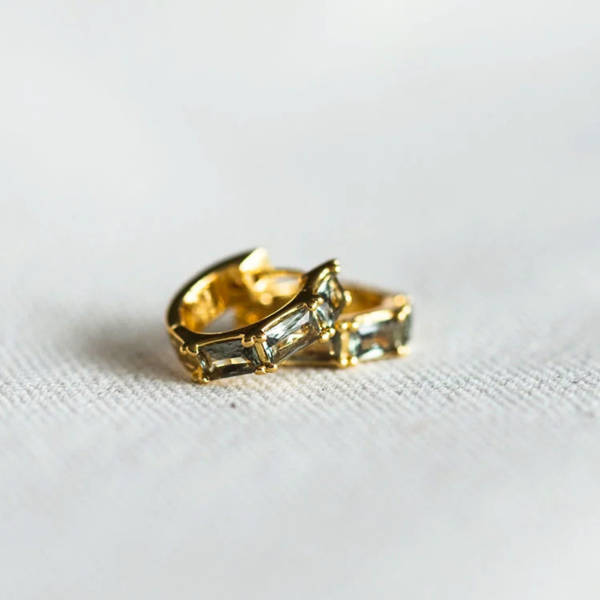 a pair of gold hoop earrings with stones inside. 