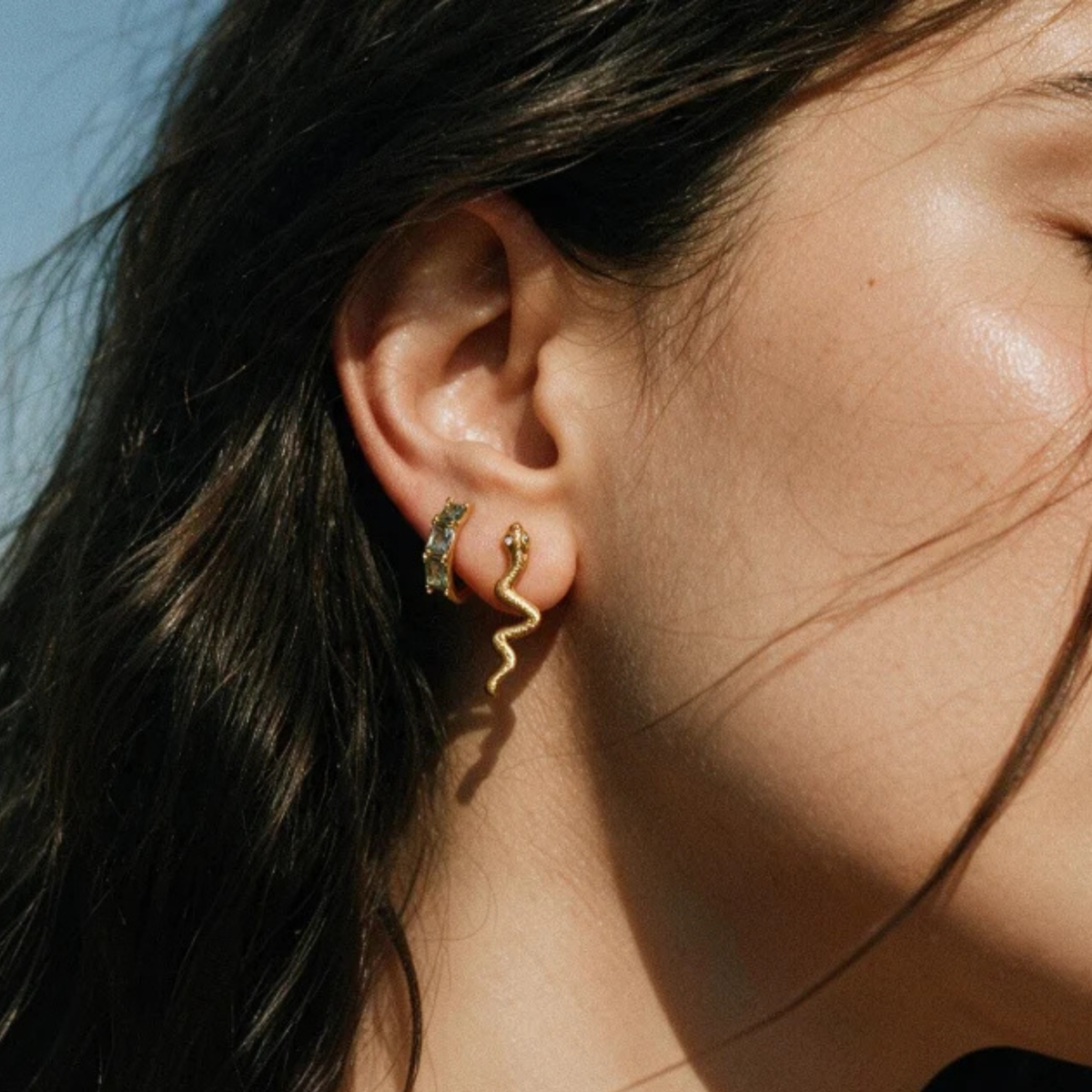 a pair of gold hoop earrings with stones inside. 