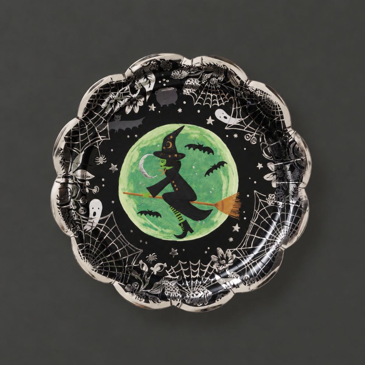A black and silver paper plate with a witch design in the center. 