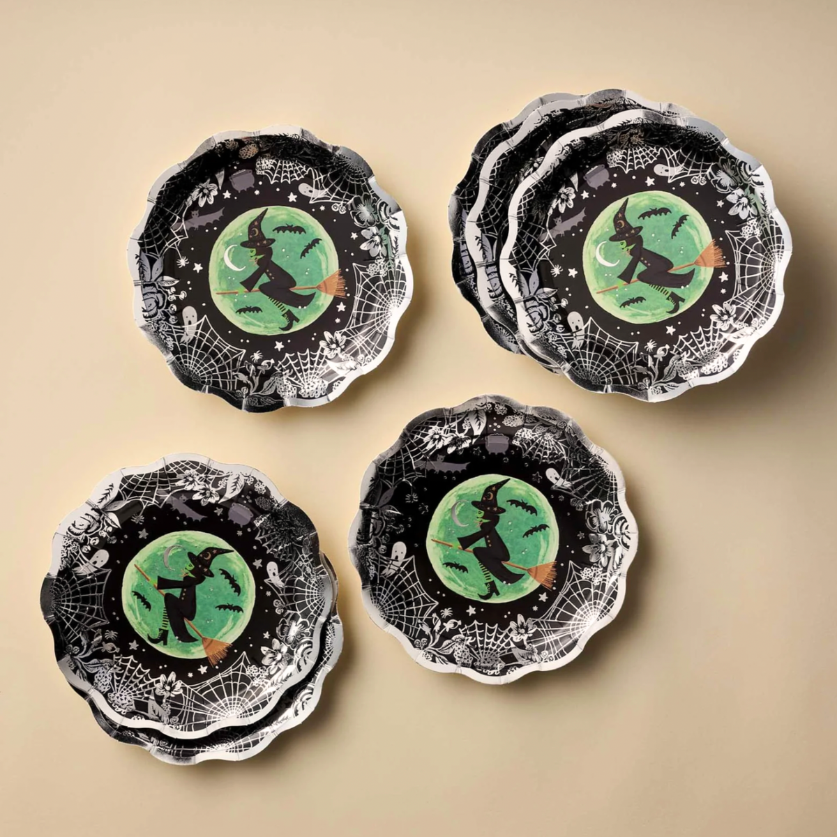 A black and silver paper plate with a witch design in the center. 