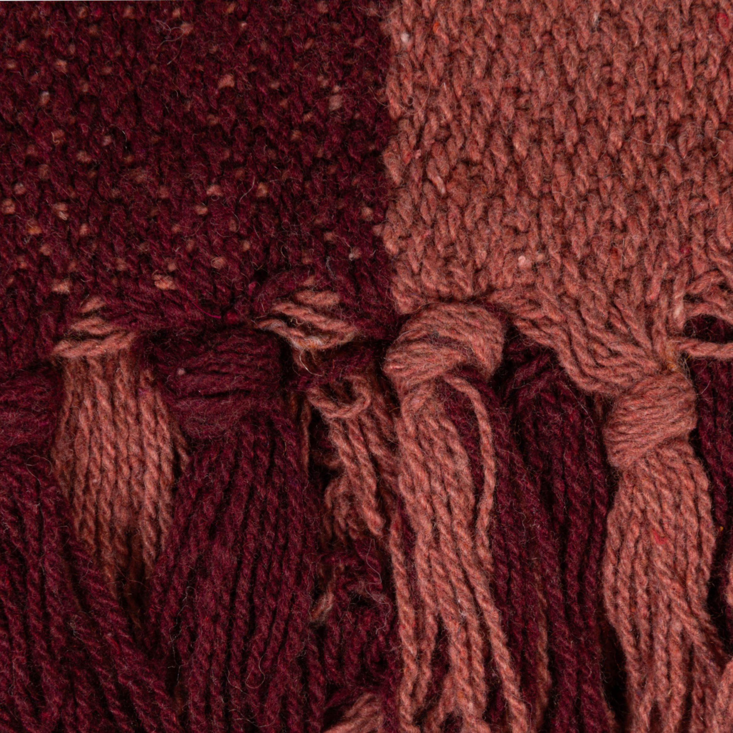 a pink and burgundy woven throw blanket.
