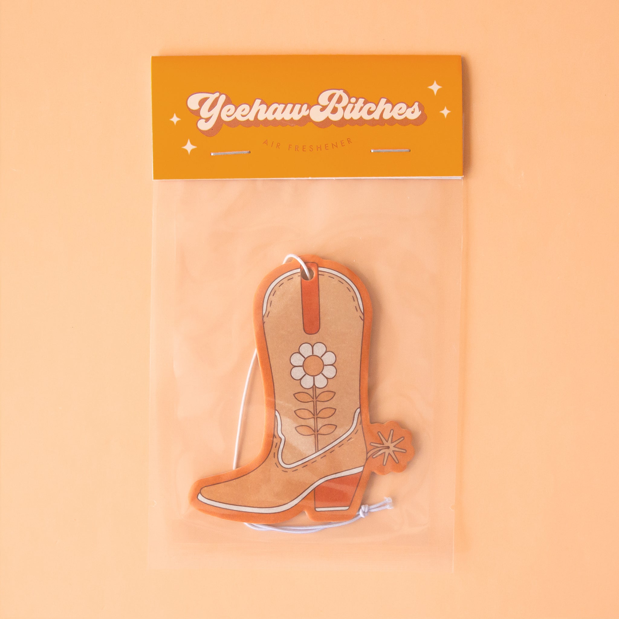 An orange cowboy boot shaped air freshener with a white string for hanging.