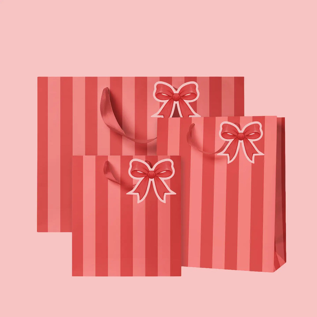 Three red and pink striped gift bags with matching ribbon handles and bow cutouts, arranged on a solid pink background.