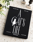 A black photo album book cover with white text that reads, 'A Cat's Life'.
