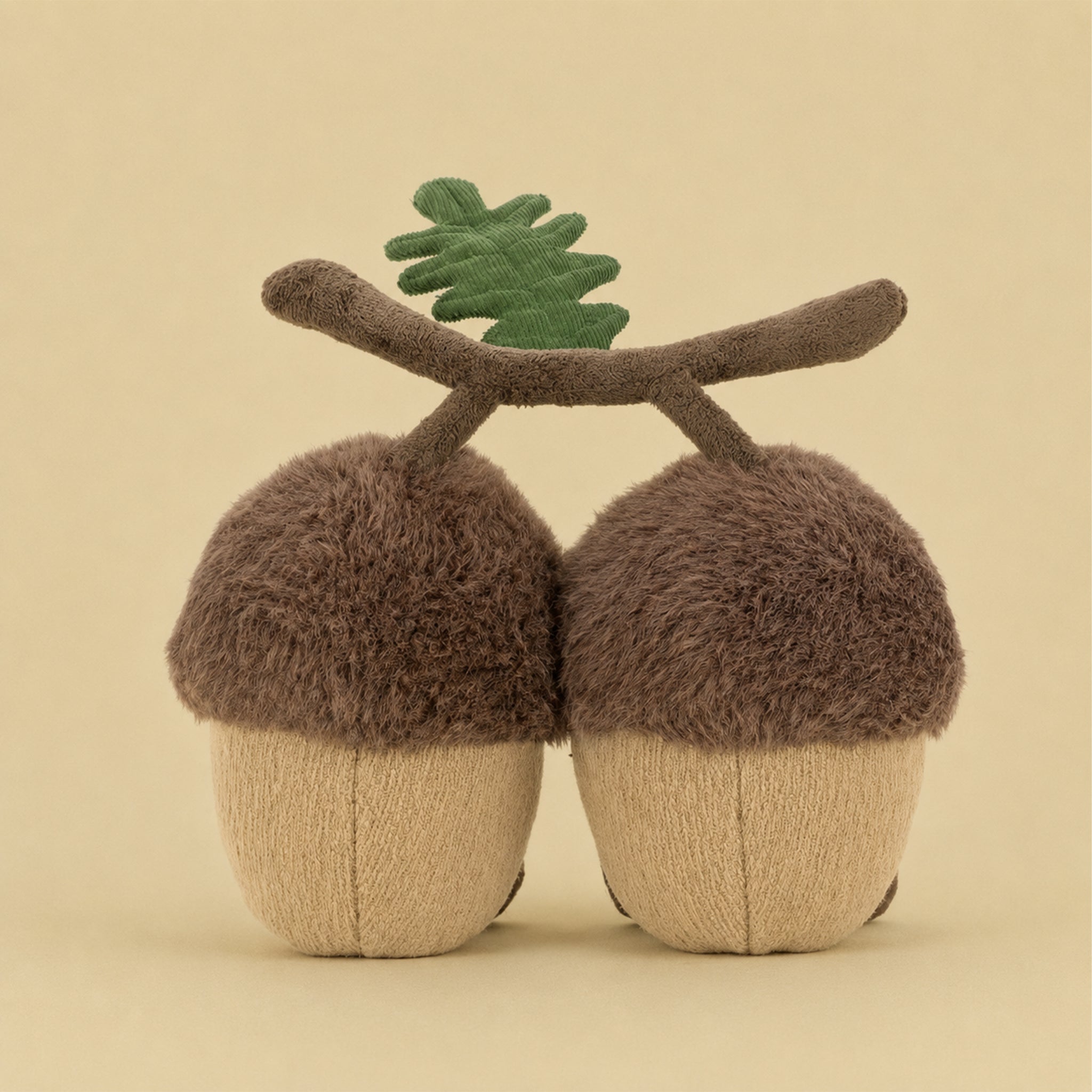 Two plush acorn toys with smiling faces on a beige background
