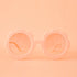 On a peachy background is a pair of flower shaped sunglasses with pink lenses and a apricot colored frame. 
