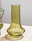 A glass green vase with a bottle neck and wide base. 